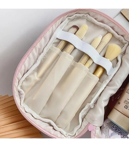 Interior detail of pink corduroy makeup bag showing brush pockets and elastic bands
