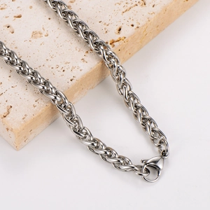Macro shot of silver stainless steel wheat chain necklace with lobster clasp detail