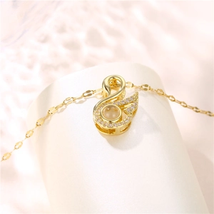 Golden swan pendant necklace with small crystals and central stone projection in titanium steel