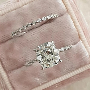 Close-up of cushion cut wedding ring set with transparent stones in pink velvet box