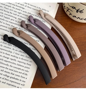 Detailed view of matte banana hair clips in various colors on a wooden table setup