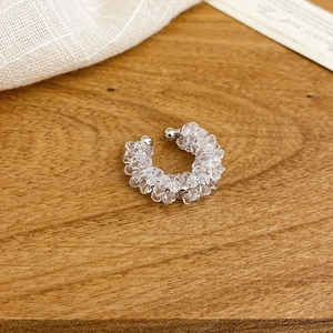 Macro shot of elegant floral beaded ear cuff with clear crystal beads on a wood surface