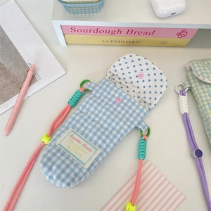 Detailed view of heart-quilted blue gingham camera pouch with colorful braided rope strap