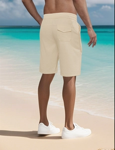 Rear view of loose fit beige summer shorts for men on a sunny beach setting