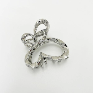 Detail of silver butterfly metal hair claw clip with wavy texture on white background