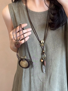 Detail of vintage leather necklace with star and feather charms on green outfit