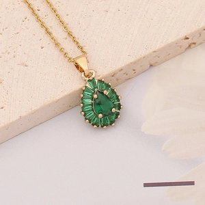 Macro shot of a vintage gold necklace with pear-shaped emerald and baguette-cut stones