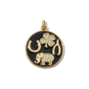 Detailed view of round gold luck charm with black enamel and sparkling zircon motifs