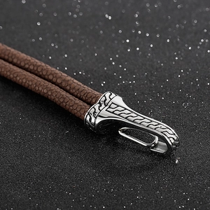 Macro shot of brown leather cord and vintage silver metal clasp with ornate engraving