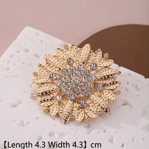 Détail d'une broche tournesol dorée de 4,3 cm avec strass brillants sur une roche