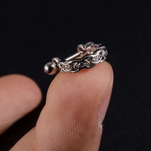 Close-up of silver-tone stainless steel ear piercing with zircon-encrusted leaf design