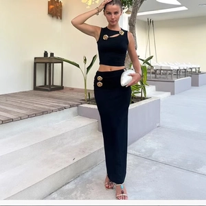 Women's black knit two-piece set featuring cropped top and maxi skirt with gold flower detail