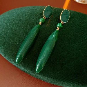 Macro view of vintage style green malachite drop earrings on a dark velvet display pad