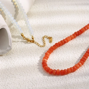 Detail of 18K gold plated necklaces with natural white opal and red agate beads