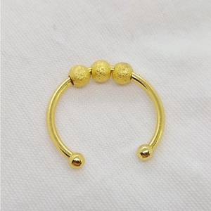Nahaufnahme eines goldfarbenen, offenen Fidget-Rings mit drei rotierenden Perlen.