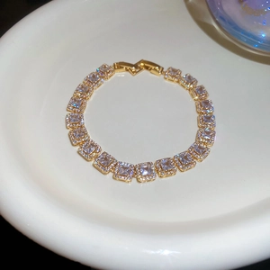 Détail d'un bracelet doré avec des zircons rectangulaires dans un plat en céramique