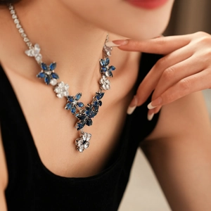 Detail view of a floral zircon necklace set with blue and white crystals on a model