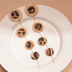 Macro detail of leopard print leather earrings with textured gold metal discs