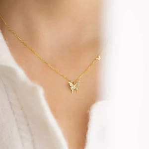 Exquisito collar de mariposa dorado con circonitas cúbicas usado por una modelo