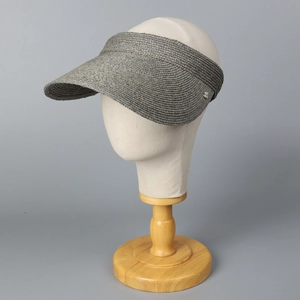 Detalle del tejido denso de rafia y emblema metálico en una gorra visera gris