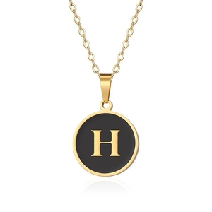 Dettaglio collana in titanio dorato con pendente tondo in smalto nero e lettera H dorata