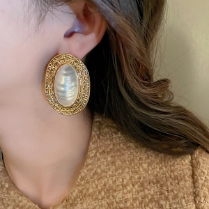 Macro detail of vintage gold textured oval earrings with oversized white pearls