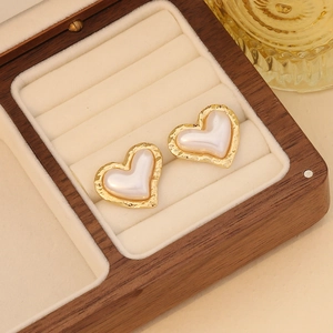 Elegant heart-shaped faux pearl earrings with textured gold frame on wooden jewelry box
