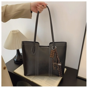 Close-up of black matte tote bag featuring white contrast stitching and cute charms