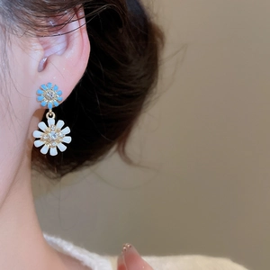 Close-up of model wearing double-layered daisy drop earrings with blue and white petals