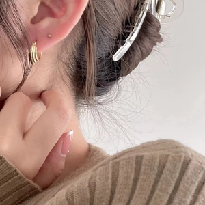 Detailed view of triple-layered golden hoop earrings and large acrylic hair claw clip