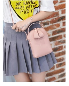 Detail view of mini pink crossbody bag with decorative leaf zipper pulls worn by model