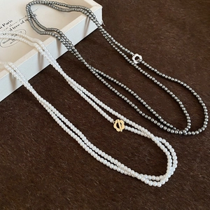 Detail view of multi-layer pearl necklaces with floral clasps in white and dark grey