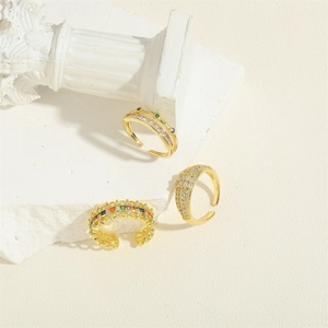Three luxury gold adjustable rings with colorful zircon stones on white marble pedestal