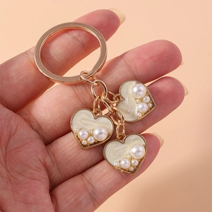 Elegant gold metal keychain with beige enamel heart charms and pearl embellishments