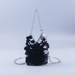 Detail of black large sequins fabric and silver metal chain strap on a mini bucket bag