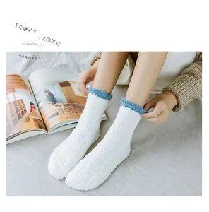 Close-up of thick white coral fleece socks with blue scalloped edges for cozy home comfort