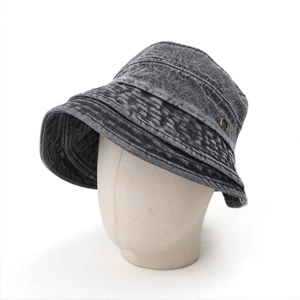 Retro washed grey denim bucket hat with wide brim and vintage metal emblem on studio mannequin