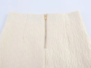 Gros plan sur la fermeture éclair invisible et le tissu en tweed texturé de la jupe courte