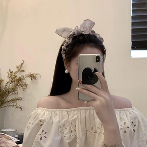 Detail of light brown floral bow headband with soft fabric texture and pleated design