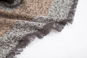 Close-up of brown and gray plaid wool scarf showing thick texture and fringe tassels