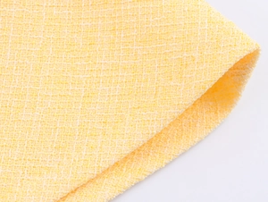 Vista macro dettagliata della trama del tessuto tweed giallo con motivi intrecciati