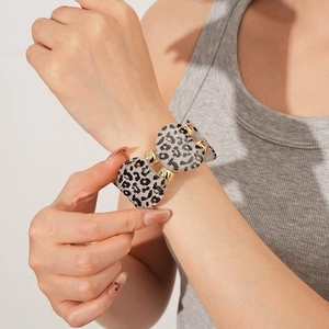 Detail of leopard print resin watch band with gold connectors on woman wrist