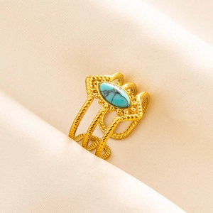Detail of gold woven ring featuring a central oval turquoise stone on soft beige fabric