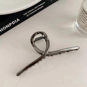 Detail of a large silver twisted metal hair claw clip displayed on a minimalist desk