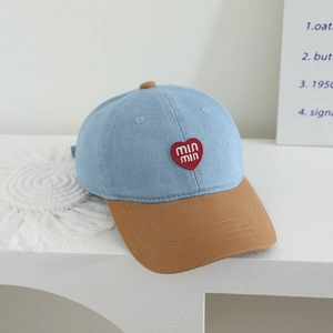 Detail of color-block denim kids baseball cap with red heart embroidery on white pedestal