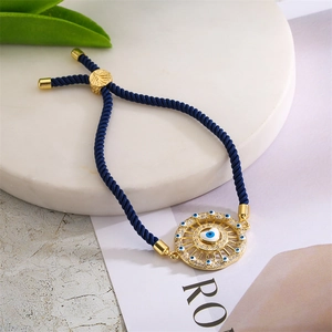 Detailed close-up of navy braided evil eye bracelet with heart charm on white stone stand