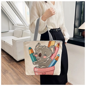 Lifestyle shot of linen tote bag featuring a cute cartoon koala print and striped straps