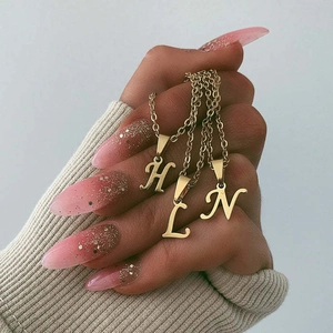 Gold titanium steel letter necklaces with H, L, N pendants held by hand in style
