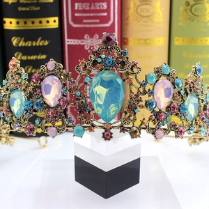 Close-up of vintage gold bridal crown with colorful rhinestones and pear-shaped blue stone