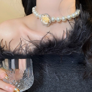 Detail of multi-layer pearl necklace with a rhinestone floral pendant on a model